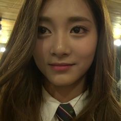 a woman with long hair wearing a tie and looking at the camera while standing in a room