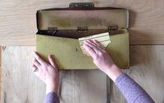 a person is holding a piece of paper in front of an old suitcase on the floor