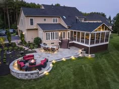 an aerial view of a house with patio and seating area in the yard at dusk