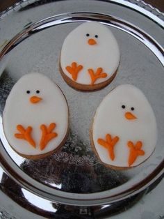 three decorated cookies sitting on top of a silver plate with frosting and orange decorations