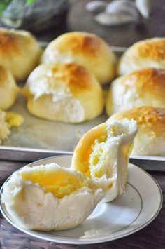 there are some bread rolls on the plate and one has an egg yolk in it