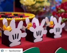 there are some small boxes with ears on them sitting on a table next to flowers