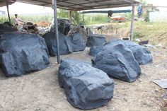 several large rocks sitting under a shelter on top of a dirt field next to a man