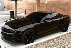 a black chevrolet camaro parked in front of a building