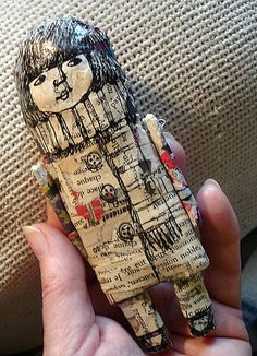 a person holding up a piece of art made out of newspaper and paper mache