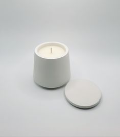 a white candle sitting on top of a table next to a round object with a wooden stick sticking out of it