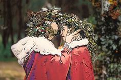 two people dressed as santa claus kissing in front of some trees and bushes with leaves on them