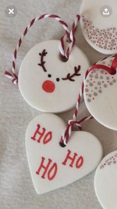 christmas ornaments are hanging on a white sheet with red and white twine around them