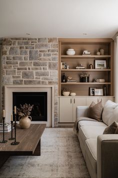 a living room filled with furniture and a fire place in front of a brick wall