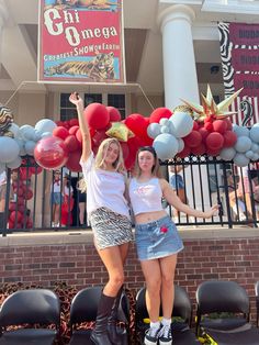 two young women standing next to each other in front of a building with balloons on it