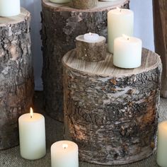 some white candles sitting on top of logs