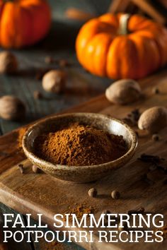 a bowl filled with cinnamon and nuts on top of a wooden cutting board next to pumpkins