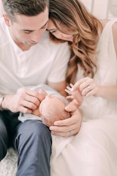 a man and woman holding a baby in their arms while sitting on a bed together