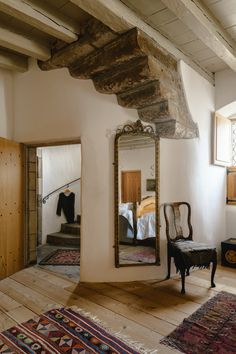 a mirror sitting on top of a wooden floor next to a chair and rugs