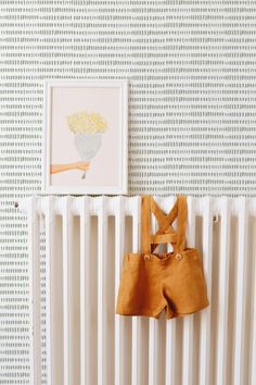 a baby's clothes hangs on the radiator in front of a painting