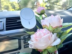 two pink flowers sitting in the center console of a car next to an air vent