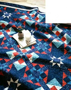 a blue quilt with red, white and blue stars on it next to a laptop