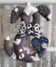 a crocheted wreath hanging on the front door with a dog's paw print