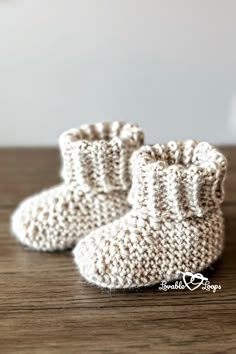 a pair of crocheted baby booties sitting on top of a wooden table