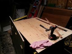 an electric driller on top of a wooden table in a room with other tools