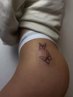 a woman's thigh with two butterflies on it and the bottom part of her leg