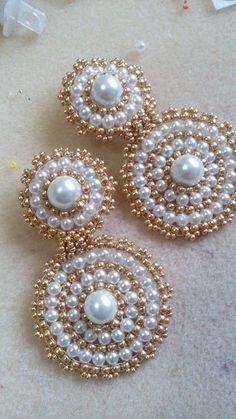 three white and gold beaded earrings sitting on top of a table