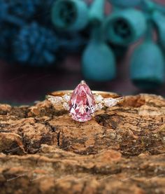 a pink diamond ring sitting on top of a rock