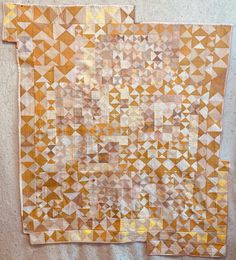 an orange and white quilt hanging up on a wall next to a pair of scissors