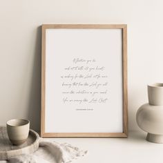 a framed quote on a white wall next to two vases and an empty cup