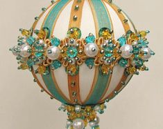 an ornament with beads and jewels on it is hanging from a hook in the shape of a ball