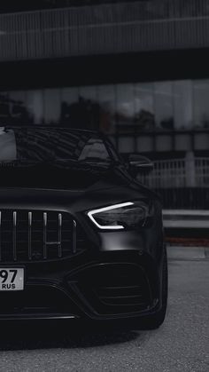 the front end of a black mercedes s - class cab parked in front of a building