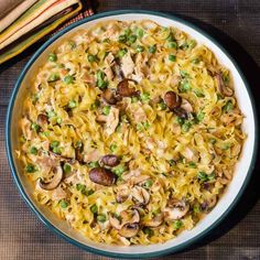 a bowl filled with noodles and mushrooms on top of a table