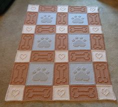 a crocheted blanket is laying on the floor next to a cat paw rug