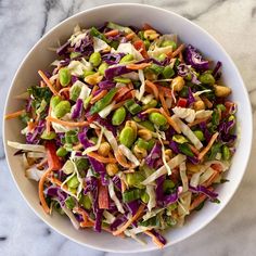 a white bowl filled with coleslaw and carrots on top of a marble table