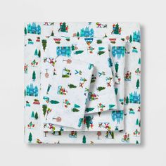 a white sheet set with blue and green christmas trees on it, along with matching sheets