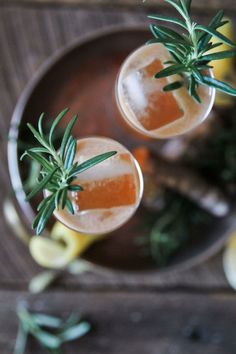 two cocktails with rosemary garnish sit on a plate