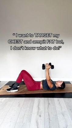 a woman laying on top of a wooden mat with dumbbells in front of her