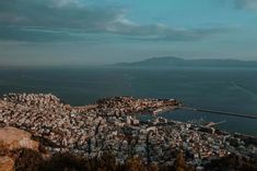 an aerial view of a city with mountains in the background and water on the other side