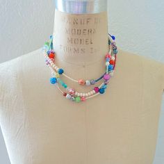 Achieve that stacked look effortlessly with this boho chic style multi-strand bib necklace. An artful mix of beads in vibrant colors and materials, such as glass beads, floral fimo, and faux pearls are strung on 3-strands that have been twisted for a fuller attention-grabbing stacked layered look. Lobster clasp. Handmade in USA. Bohemian White Multi-strand Layered Necklace, Multicolor Beaded Multi-strand Layered Necklace, Multicolor Beaded Chain Necklaces For Layering, Multicolor Beaded Chain Necklace For Layering, Multicolor Double Strand Bohemian Layered Necklace, Bohemian Double Strand Layered Necklace With Colorful Beads, Bohemian Multicolor Double Strand Layered Necklace, Whimsical Multicolor Beaded Necklaces, Bohemian Multicolor Beaded Necklaces For Layering