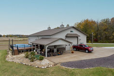 a red truck is parked in front of a large building with a covered porch and garage