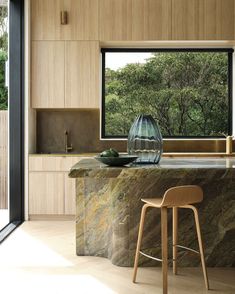 a modern kitchen with marble counter tops and wooden cabinets, along with a bar stool