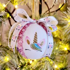 an ornament hanging from a christmas tree decorated with pink and gold sequins