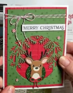 someone holding up a christmas card with a deer on it