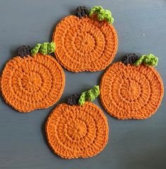 four crocheted pumpkin coasters sitting on top of a table