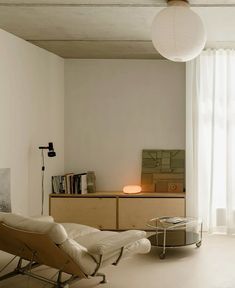 a living room filled with furniture next to a window covered in white curtains and lights