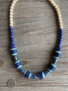 The beautiful ceramic beads are navy blue with light blue stripes.  The accent beads are coconut wood in navy and light blue.  This color combination will be so beautiful this Spring and Summer with jeans or a dress.  It will be a most loved piece in your accessory wardrobe one. Blue Bohemian Wooden Beads Necklaces, Adjustable Blue Necklace With Wooden Beads, Ocean-inspired Blue Beaded Necklace, Handmade Blue Shell-shaped Necklace, Handmade Blue Multi-strand Necklace, Blue Beaded Shell-shaped Necklace, Navy Necklace, Blue Multi-strand Wooden Bead Necklaces, Coconut Wood