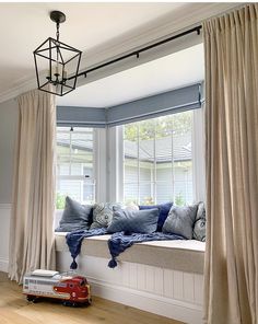 a window seat with pillows on it and a toy car in front of the window