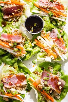 lettuce wraps with meat and vegetables on a white platter topped with sauce