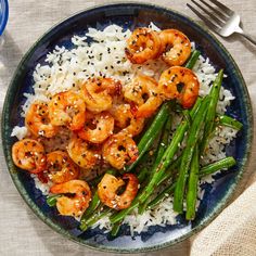 a blue plate topped with rice and shrimp on top of a table next to a bottle of water