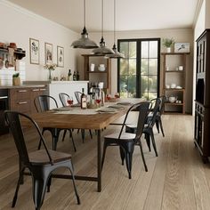 a dining room table and chairs in front of an open kitchen with sliding glass doors